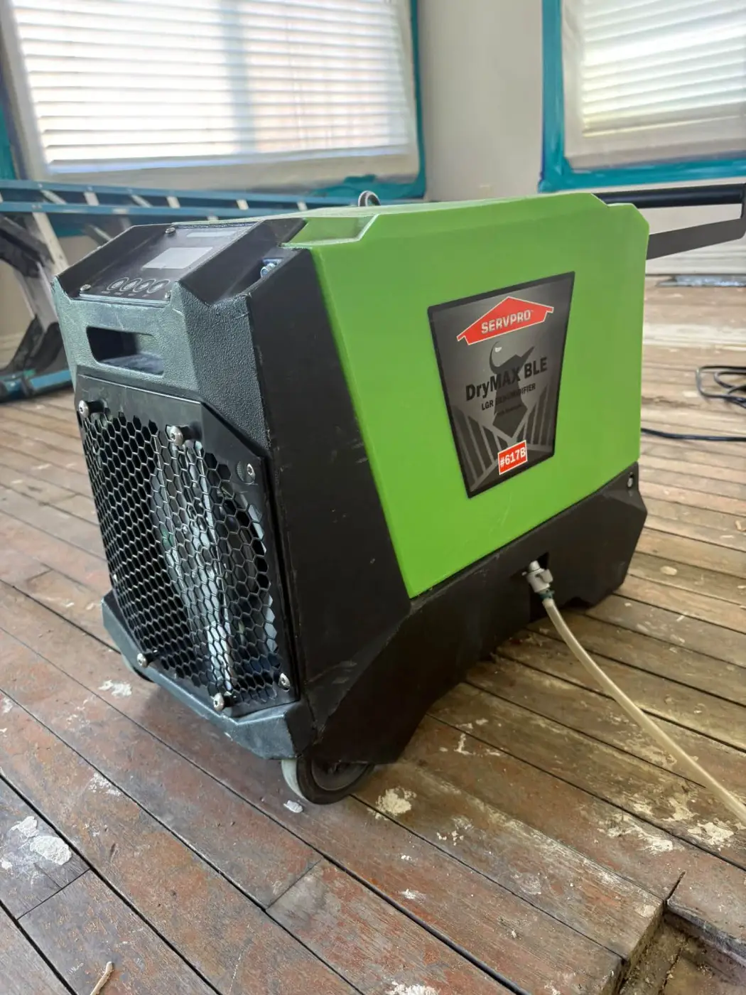 Dehumidifier drying an exposed subfloor beside an opening in the floor