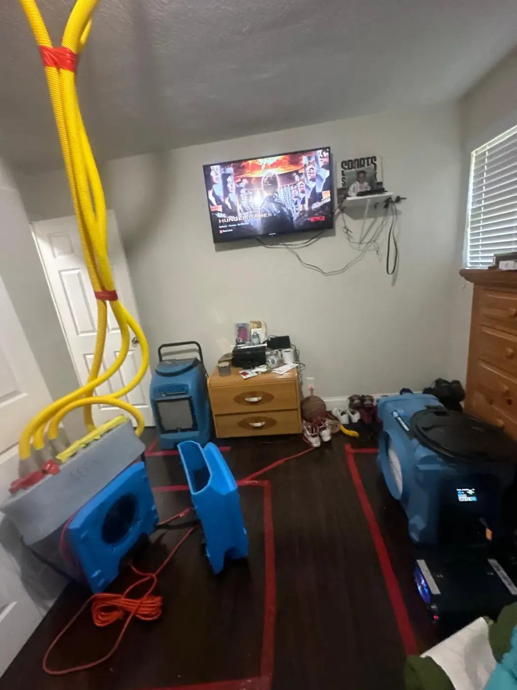 Air movers, a dehumidifier and drying hoses set up in a bedroom